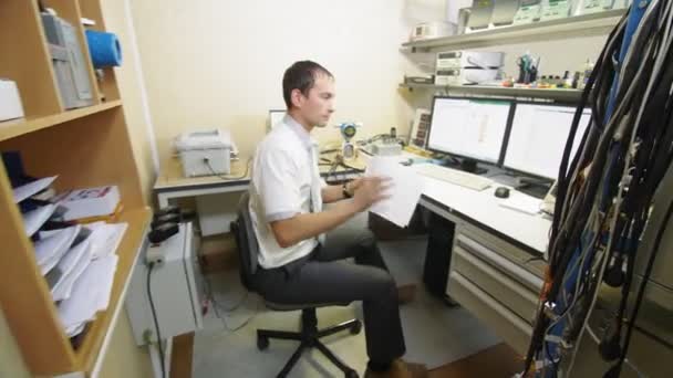 Mérnök veszi papírokat dolgozik asztalnál monitorok — Stock videók