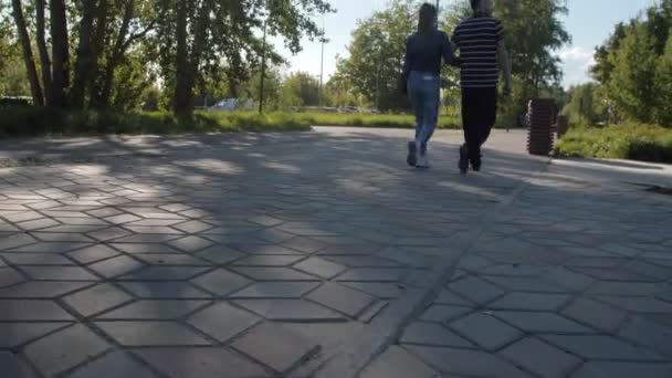 Mężczyzna i kobieta przechodzą obok świeżych trawników w zielonym wiosennym parku — Wideo stockowe