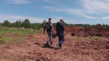 İşçiler petrol sahasındaki derin çukurlara bakıyorlar.