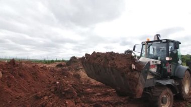 İnşaat alanı boyunca çöp dolu kazıcı.