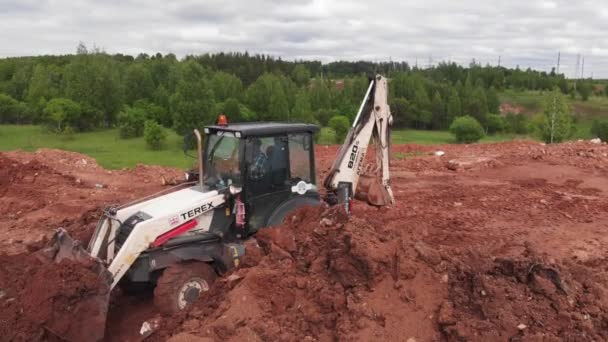 Muncitor conduce săpător cu sol în găleată la șanț — Videoclip de stoc
