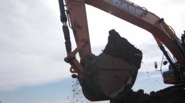 Kazıcı kamyonu inşaat alanında kovayla toprak alıyor.