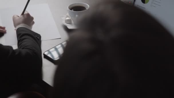 Женщина пишет сидя рядом с коллегой за столом с ноутбуком — стоковое видео