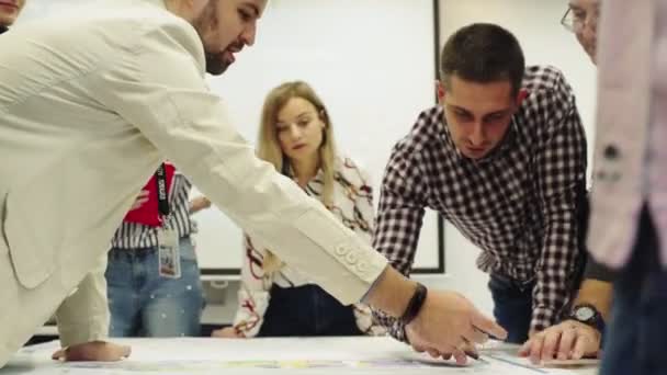 Équipe de jeunes et senior man travaillent avec le dessin à table — Video