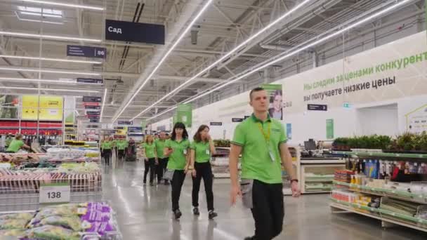 Vendedores em camisetas caminham pelo caminho no supermercado de jardinagem — Vídeo de Stock