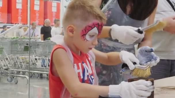 Pojke med spiderman bild lär sig att polera träblock — Stockvideo
