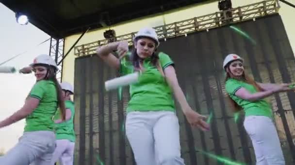 Mujeres bonitas en trajes de constructor con rodillos bailan en el escenario — Vídeo de stock