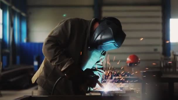 Maskeli ve üniformalı işçi dükkandaki kıvılcımlarda parçaları kaynaklıyor — Stok video