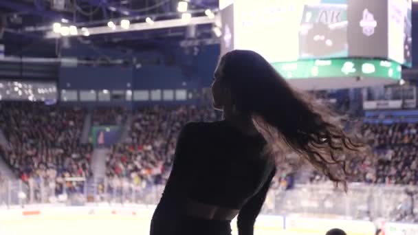 Cabelo encaracolado cheerleader dança com pompons no estádio — Vídeo de Stock
