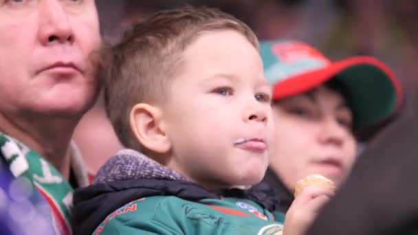 Chłopiec je lody oglądając mecz hokeja z dziadkiem — Wideo stockowe