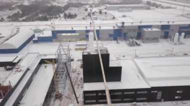 Kamyon vinci kışın atölye üzerinde silindirik bir detay tutar