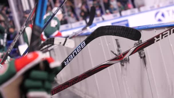 Дивіться на гілочки хокейної команди, які сидять на лавці біля льодової арени. — стокове відео