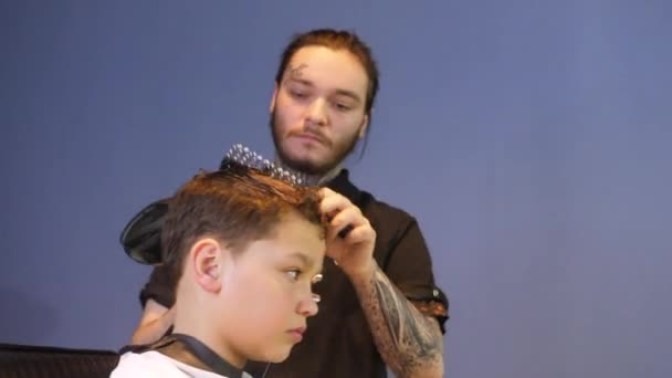 有纹身的理发师在沙龙里给十几岁的男孩做发型 — 图库视频影像