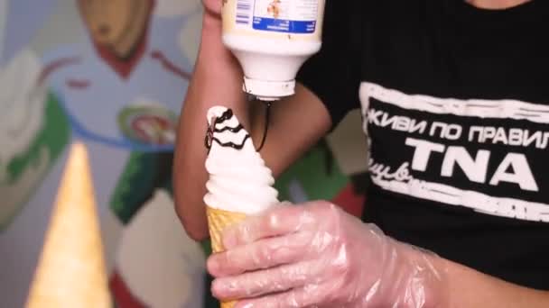 Молодой человек наливает шоколадный сироп на мороженое в кафе — стоковое видео