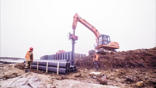 Tumpukan penggali di bawah kontrol pekerja di konstruksi — Stok Video