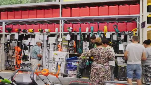 Kunden wählen Rasenmäher am Regal im Gartenmarkt — Stockvideo