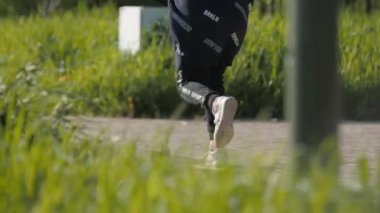 Siyah ceketli genç kız park boyunca kaykay sürüyor.