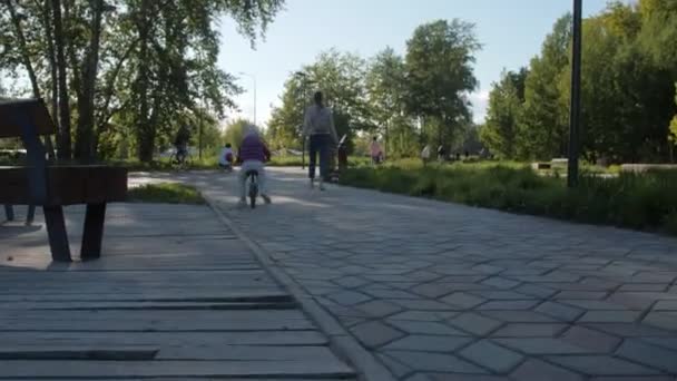 Yürüyen çocuk, annenle parkta yürürken pistte bisiklet sürüyor. — Stok video