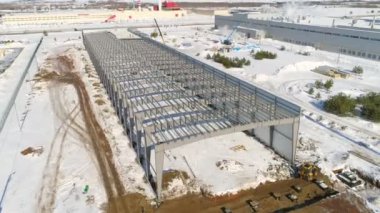 Karlı fabrika şantiyesinde kirişleri olan gri bir leş.