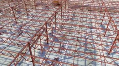 Kırmızı metal iskelet ve karlı alanda tamamlanmamış bina.