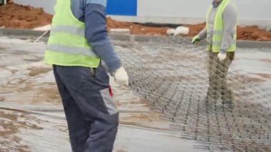 İşçiler fabrika inşaatı boyunca metal şebekeler taşıyorlar