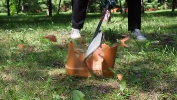 Człowiek łamie garnek kijem hokejowym na zielonym trawniku w słonecznym parku — Wideo stockowe