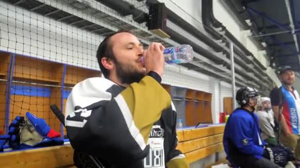 Χόκεϊ παίκτης πίνει νερό και γελάει στον πάγκο στην προπόνηση — Αρχείο Βίντεο