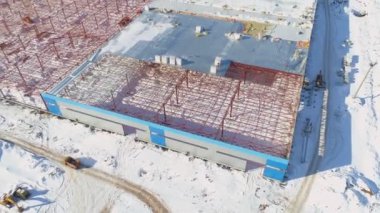 Karlı inşaat alanında kırmızı metal leşli bir depo.