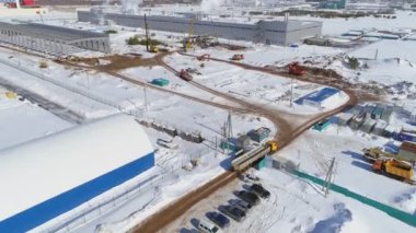 Kamyon, açık karlı inşaat alanında yol boyunca sürüyor.