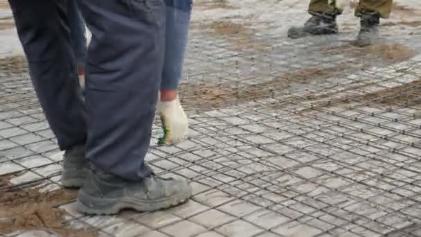 일꾼들은 플라스틱 포일로 덮여 있는 땅에 금속 격자를 놓는다 — 비디오