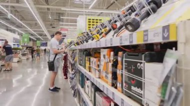 İnsan geniş bir mağazanın yanında duran matkabı seçer