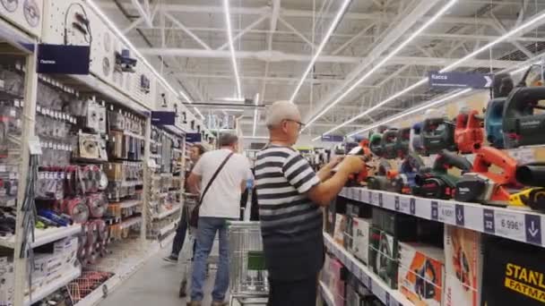 Senior man väljer ny polermaskin nära display — Stockvideo