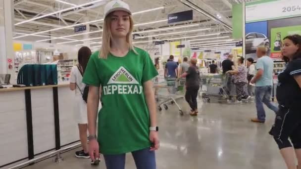 Pretty woman in t-shirt with inscription Leroy Merlin Moved — Stock Video