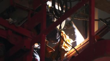 Çalışan, inşaat alanındaki ekipmanlarla metal parçaları kaynaklıyor