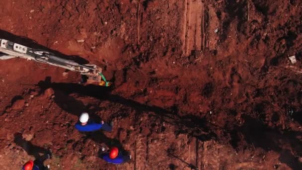 Skopa av grävmaskin över dike och byggare på plats — Stockvideo