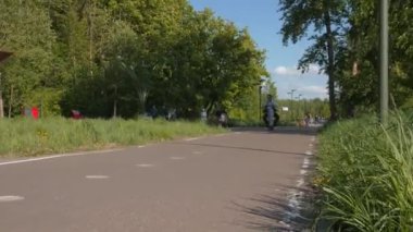 Babası ve kızı park boyunca elektrikli scooter kullanıyor.