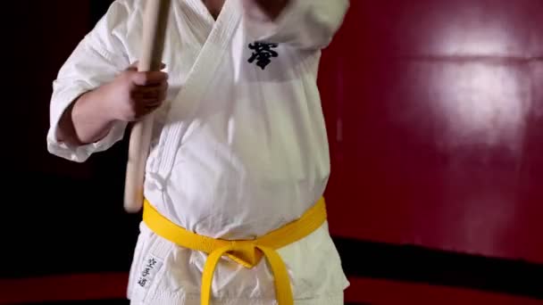 Man in kimono with yellow belt trains with stick in gym — Stock Video