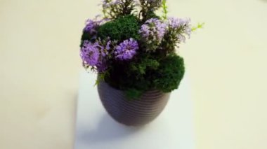 Yapay çiçekler ve sarı vazoda yapraklar.