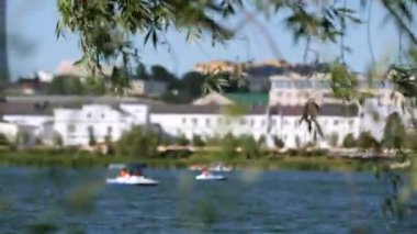 Söğüt dalları rüzgarla dalgalandı ve insanlar yelkenli botlarla yelken açtı.