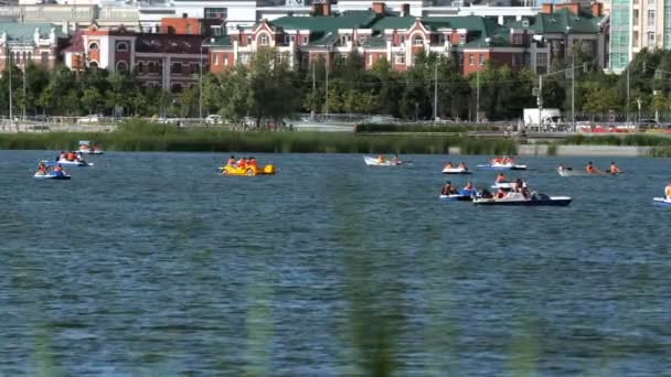 Туристы плавают на разных лодках вдоль спокойного озера — стоковое видео