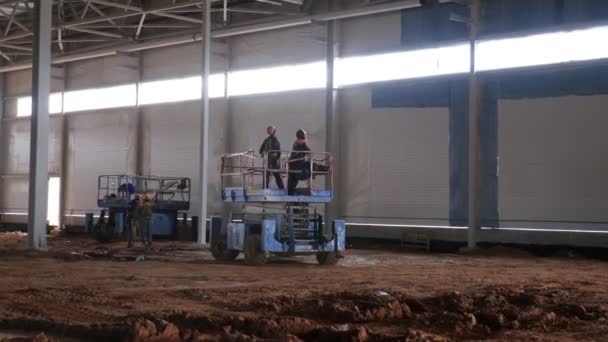 Arbeiter in Uniform fahren Scherenstapler durch Werkstatt — Stockvideo