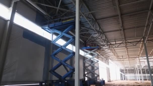 Employees install details standing on scissor lifts in shop — Stock Video