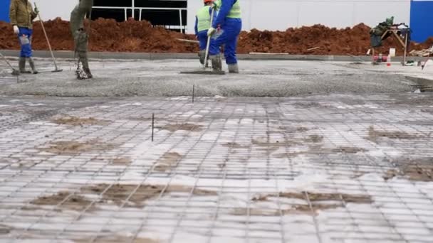 Строители разбросали мокрый бетон по земле с сеткой и фольгой — стоковое видео