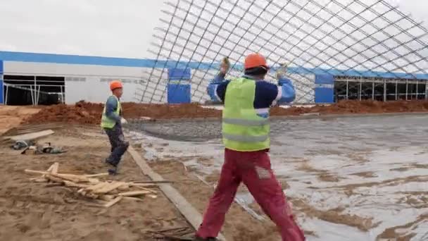 Рабочие несут большую металлическую сетку, чтобы положить ее на землю с фольгой — стоковое видео