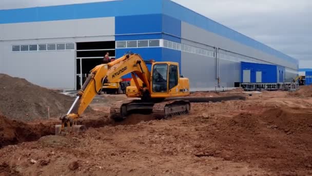 Bagger gräbt Graben mit Schaufel auf Baustelle aus — Stockvideo