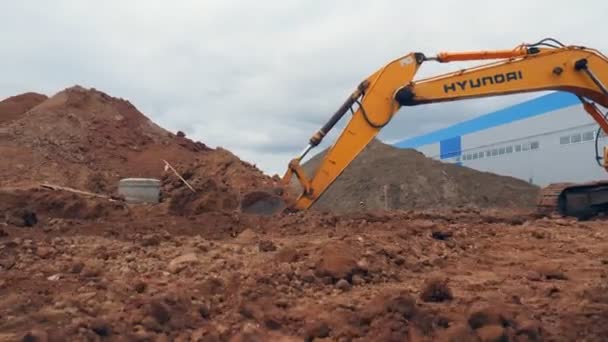Gul grävmaskin gör diket i drift på byggarbetsplatsen — Stockvideo