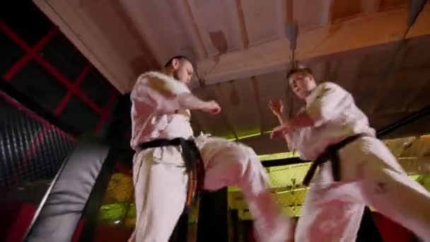 Sportler in Kimonos kämpfen in leichtem Fitnessstudio um Beine — Stockvideo