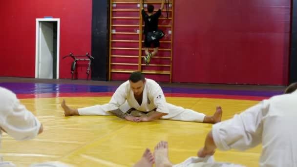 Man met studenten doet stretching oefeningen op de vloer in de sportschool — Stockvideo