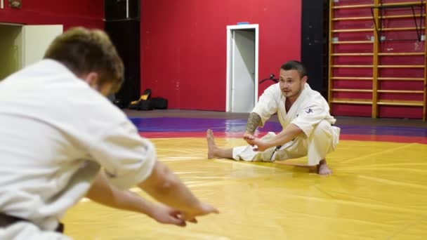 Trainer in kimono met studenten doet side lunges in de sportschool — Stockvideo