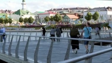 Olgun insanlar sakin bir nehrin üzerinde trabzan ile köprü boyunca yürürler.